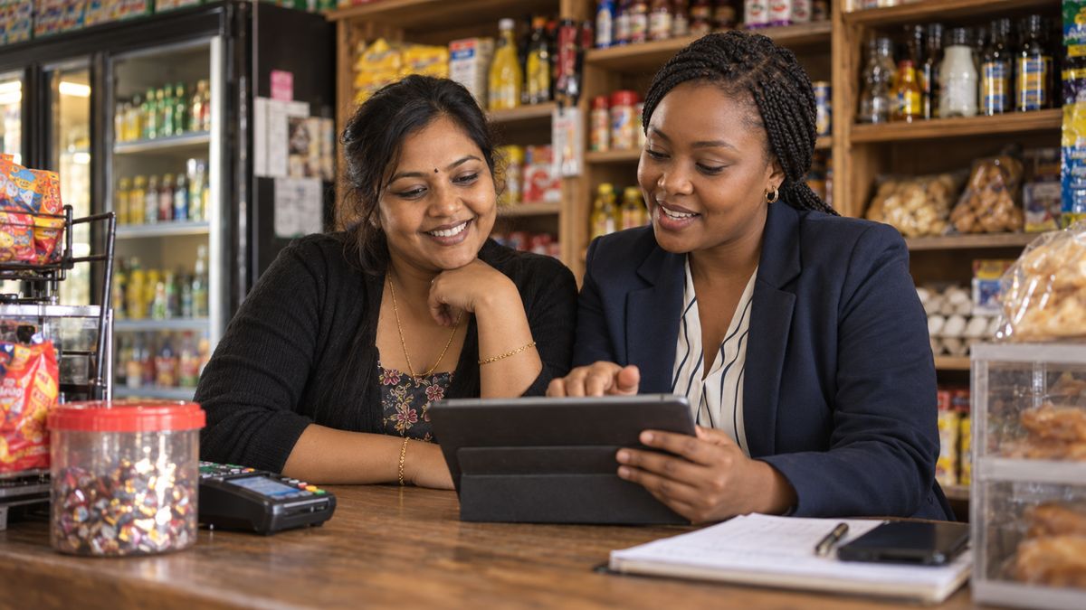 Spaza shop owner and accountant reviewing figures on a tablet at the counter